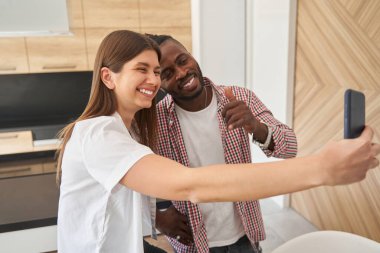 Akıllı telefon kamerası için poz veren neşeli melez çift.