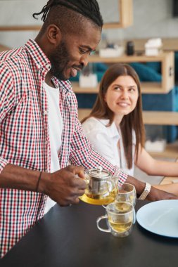 Gülümseyen mutlu adam iki kişilik papatya çayı yapıyor.