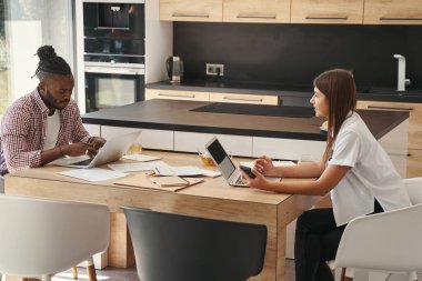 Kadın, dizüstü bilgisayarında yazı yazan ciddi bir adama bakıyor.