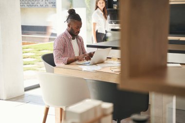 Kadın, dizüstü bilgisayarda yazan adamı izliyor.