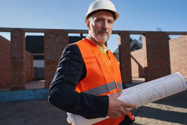 Reserverad byggare i skyddsutrustning poserar på sin arbetsplats — Stockfoto