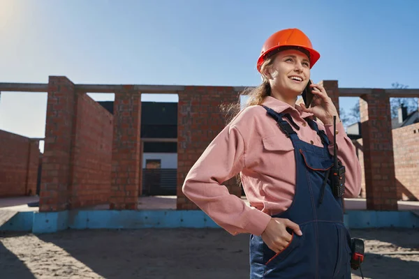Решительная дама в строительной экипировке с телефонным разговором — стоковое фото