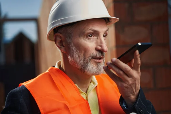 Professionell byggare som har en hektisk konversation på telefon — Stockfoto
