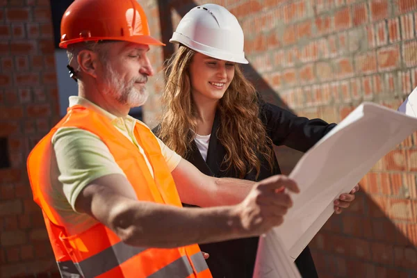 Opgewonden bouwers kijken naar de bouw whiteprints en glimlachen — Stockfoto