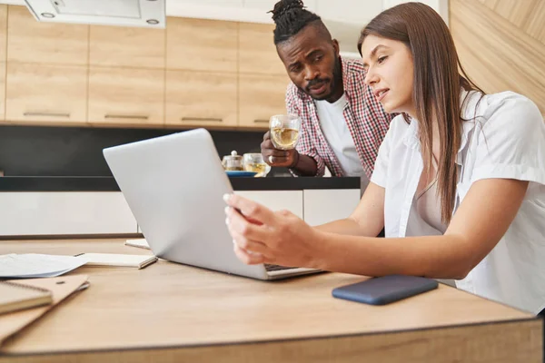 Man met theekopje en vrouw met laptop in keuken — Stockfoto