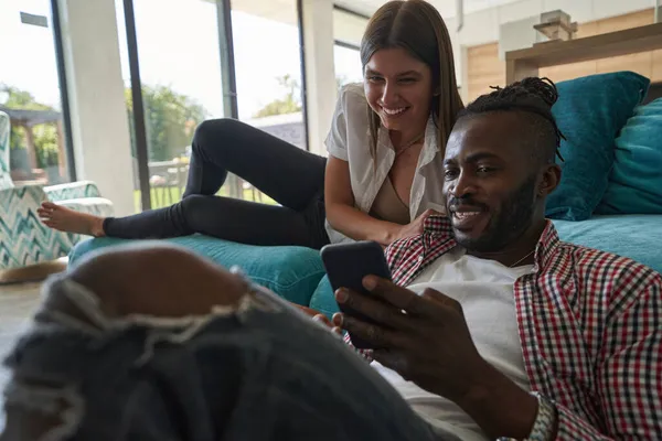 Alegre mestiço casal assistindo algo no smartphone — Fotografia de Stock