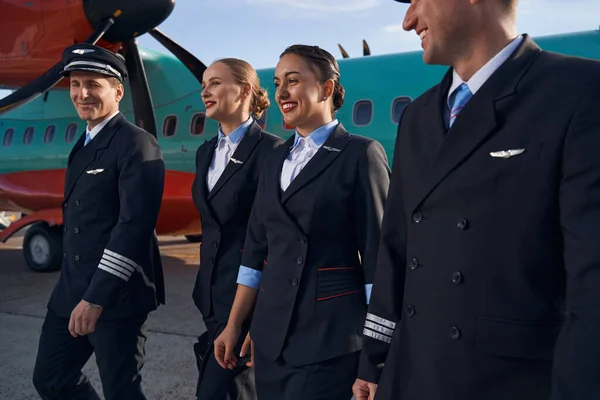 Usmívající se členové posádky letadla kráčející společně po ranveji — Stock fotografie