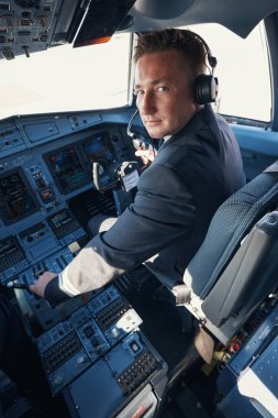 Profesyonel yardımcı pilot kokpitten kameraya bakıyor.