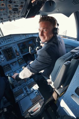 Neşeli ikinci pilot uçağı uçuruyor ve kameraya bakıyor.