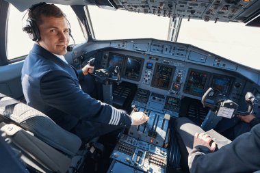 İtiş kolunu çekerken gülümseyen memnun bir uçak kaptanı.