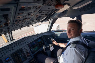 Kokpitte poz veren gülümseyen pilot.