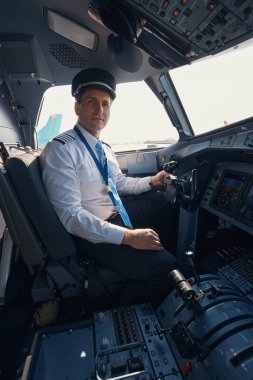 Uçak kaptanı kokpitteki koltuğundan yana bakıyor.