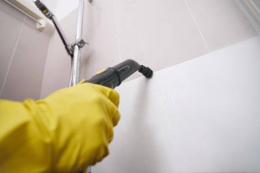 Banyo duvarında deneyimli bir işçi buhar temizleme borusu var.