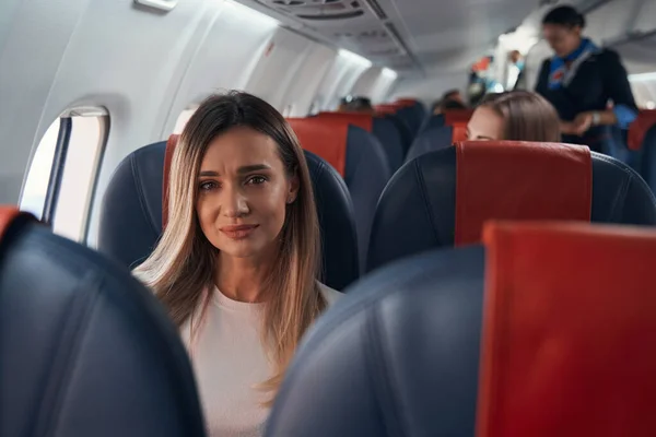 Droevige vrouw in een vliegtuig bij het raam. — Stockfoto