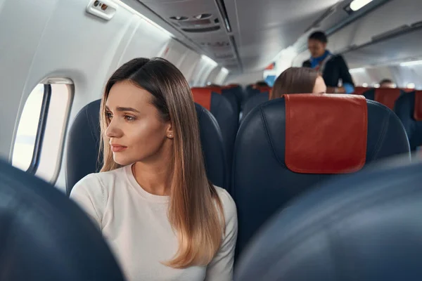 Jonge passagier kijkt uit het raam van het vliegtuig — Stockfoto
