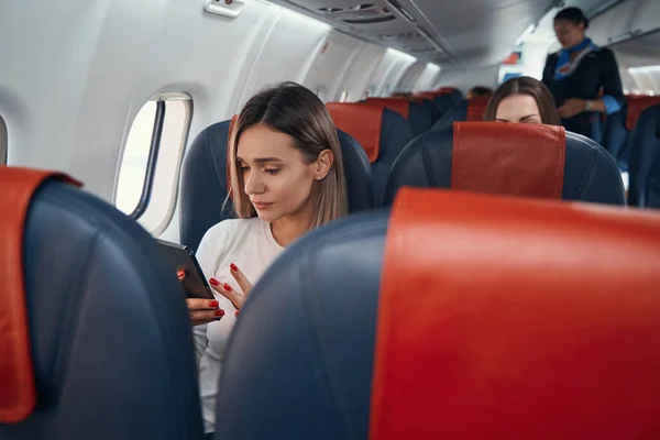 Vrouw in vliegtuigcabine klikkend op haar smartphone — Stockfoto