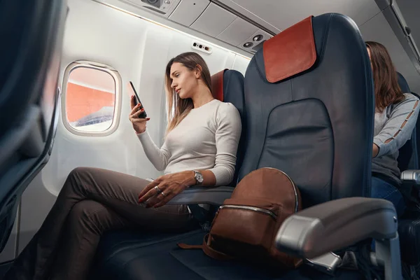 Pasajero en vuelo de avión mirando el teléfono móvil — Foto de Stock