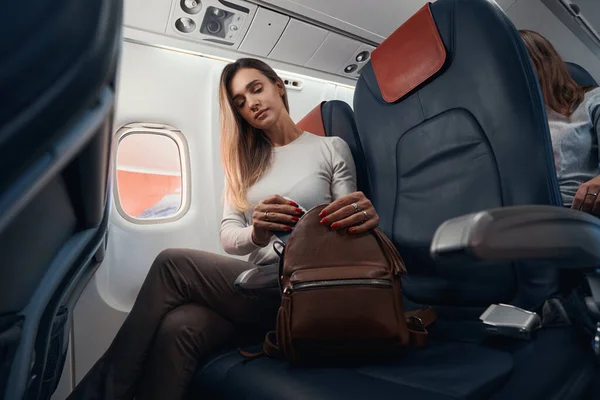 Vrouw in het vliegtuig verbergt smartphone in haar tas — Stockfoto