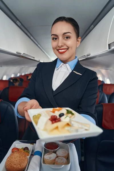 Happy flight hostess offering meal from catering trolley — Stock Photo, Image