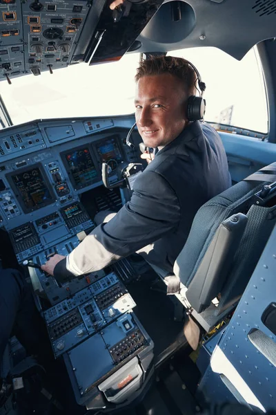 Neşeli ikinci pilot uçağı uçuruyor ve kameraya bakıyor.