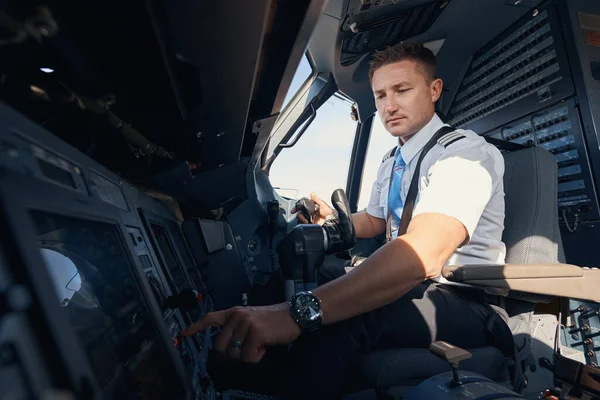 Man förste officer trycker på knappen på flygplanets kontrollpanel — Stockfoto