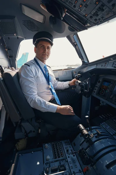 Uçak kaptanı kokpitteki koltuğundan yana bakıyor.