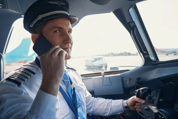 Man pilot som har ett samtal på smartphone inuti flygplan cockpit — Stockfoto