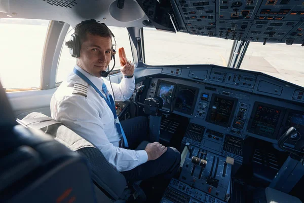 Manlig flygkapten ger tvåfingersalut till kameran — Stockfoto