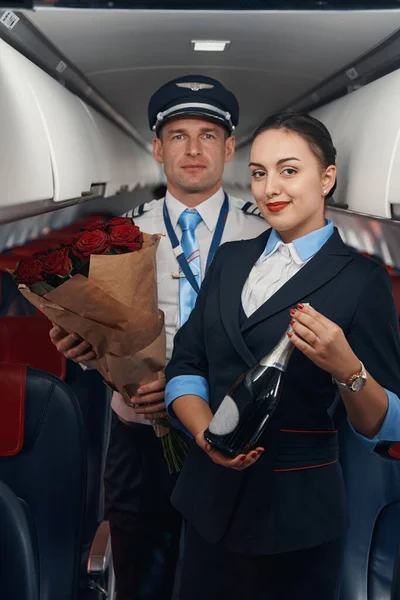 Muž pilot a letuška pobyt v kabině letadla s dárky — Stock fotografie