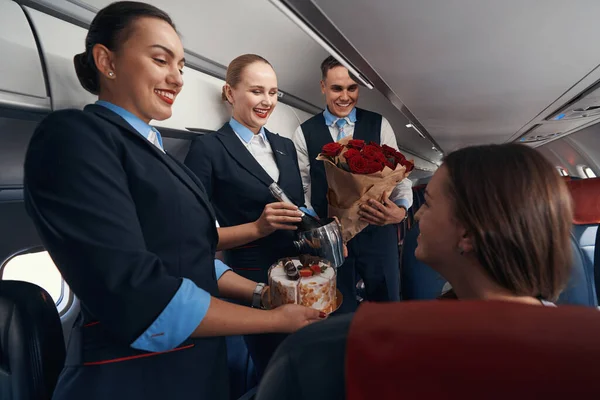 Vliegtuigcabinepersoneel dat bloemen en cake aan passagiers overhandigt — Stockfoto