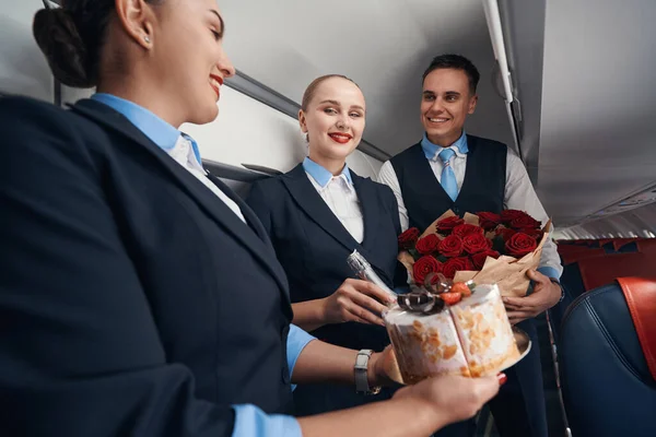 Две стюардессы женского и мужского пола с подарками с улыбками — стоковое фото