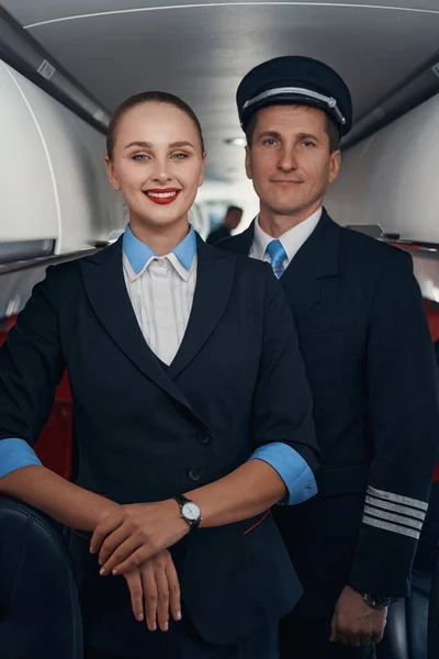 Piloto e aeromoça juntos no corredor da cabine de avião — Fotografia de Stock