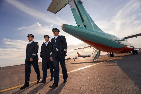 Три капітани літака роблять крок вперед від літака — стокове фото