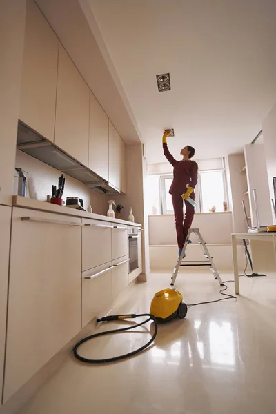 Janitor wiping recessed ceiling luminaires with damp cloth — Stock Photo, Image