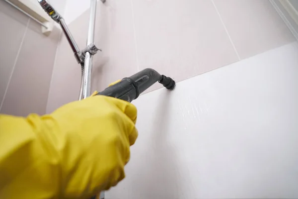 Trabalhador experiente linha de argamassa de limpeza a vapor na parede do banheiro — Fotografia de Stock