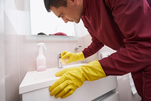 Geconcentreerde blanke mannelijke conciërge schoonmaken badkamer kraan — Stockfoto