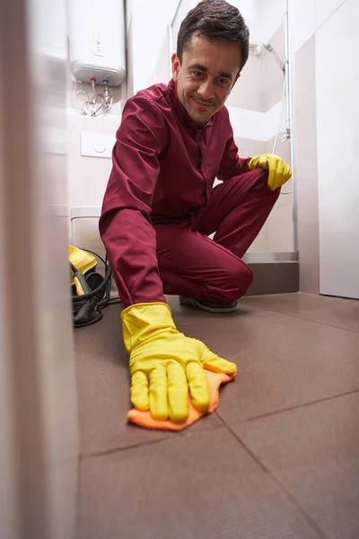 Веселая женщина в резиновых перчатках мыла пол в ванной — стоковое фото