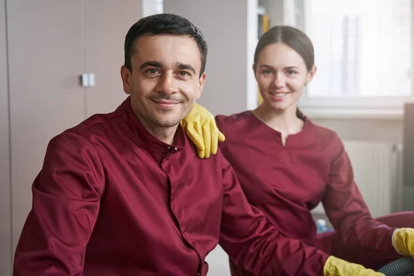 Sonriente personal de limpieza en uniformes posando para la cámara en el lugar de trabajo — Foto de Stock