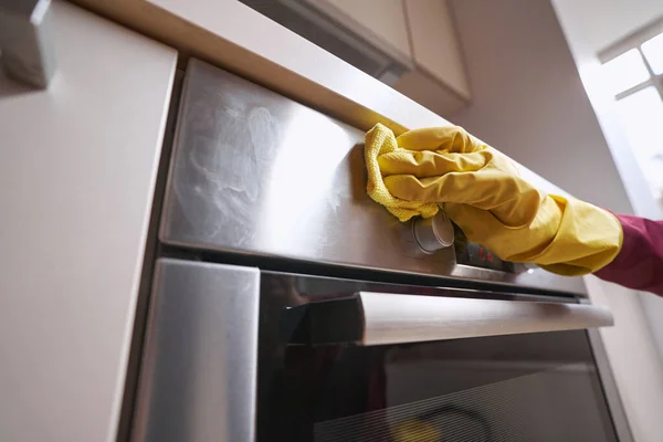 Reiniger in rubber handschoen schoonmaken stuk keukenapparatuur — Stockfoto