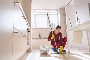 Profesyonel temizlikçi mutfakta mikrofiber paspas yapıyor.