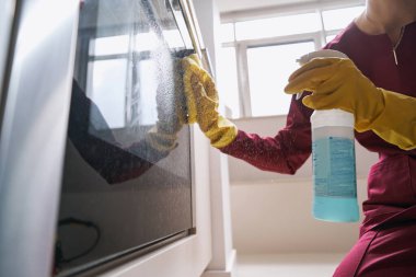 Lastik eldivenli hademe elektrikli ocağı temizliyor.