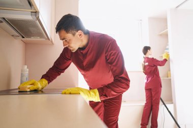 Beyaz üniformalı hademe takımı mutfağı temizliyor.