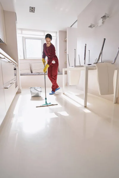 Kafkasyalı temizlikçi kadın mutfağı paspaslıyor. — Stok fotoğraf