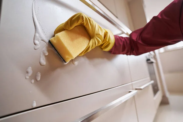 Conciërge veegt keukenkastje schoon met reinigingsoplossing — Stockfoto