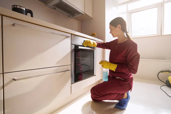 Professional cleaner wiping electric oven control panel with microfiber cloth — Stock Photo, Image