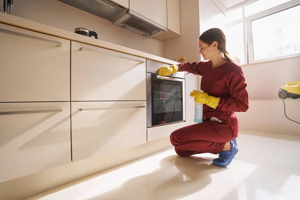 Jonge conciërge veegt keukenapparatuur af met microvezel doek — Stockfoto