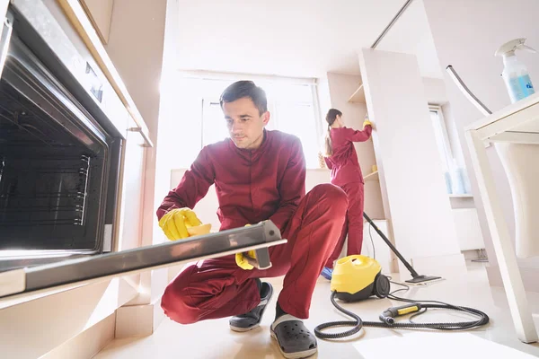 Lastik eldivenli hademe personeli mutfakta temizlik yapıyor.