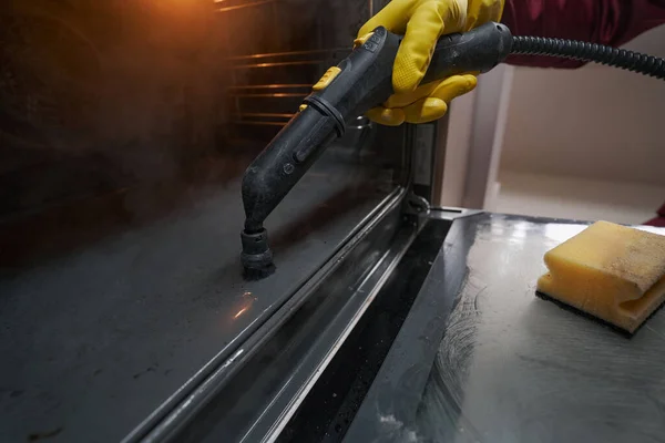 Limpiador de hogares profesional en guante de goma desinfectando electrodomésticos de cocina —  Fotos de Stock