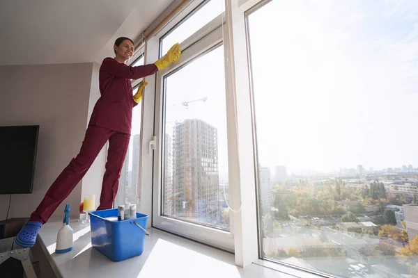 窓の上に立って窓を掃除する喜びの女性 — ストック写真
