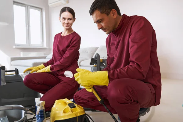 Housecleaner kijken collega tijdens het schoonmaken apparatuur assemblage — Stockfoto